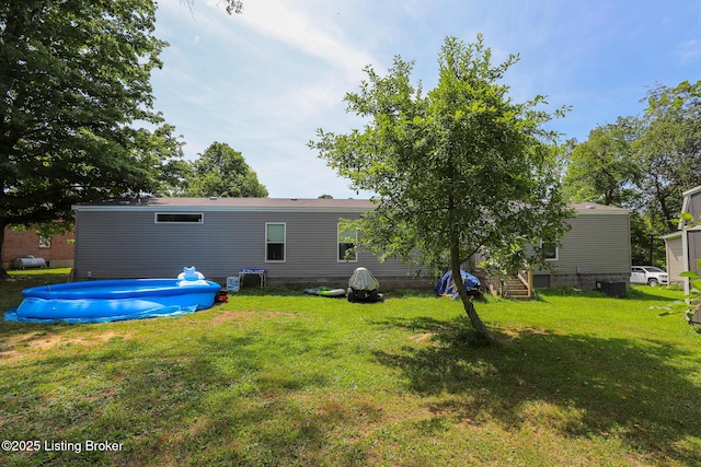 rear view of house featuring a lawn and a swimming pool