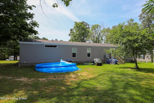 rear view of property with a yard and a pool