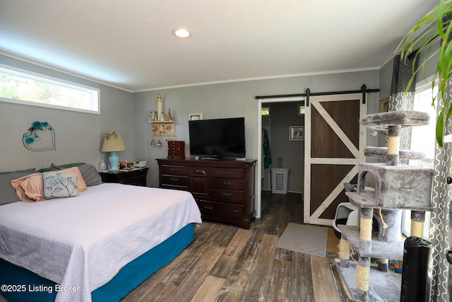 bedroom with a barn door, crown molding, and dark wood-type flooring