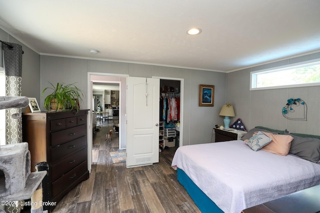 bedroom featuring dark hardwood / wood-style floors, a walk in closet, ornamental molding, and a closet