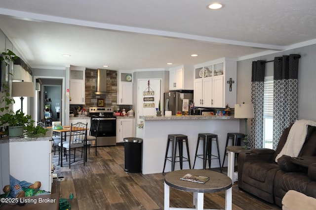 kitchen with decorative backsplash, dark hardwood / wood-style flooring, stainless steel appliances, wall chimney range hood, and white cabinets