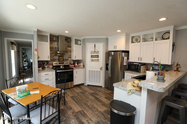 kitchen featuring backsplash, wall chimney exhaust hood, dark hardwood / wood-style floors, appliances with stainless steel finishes, and white cabinetry