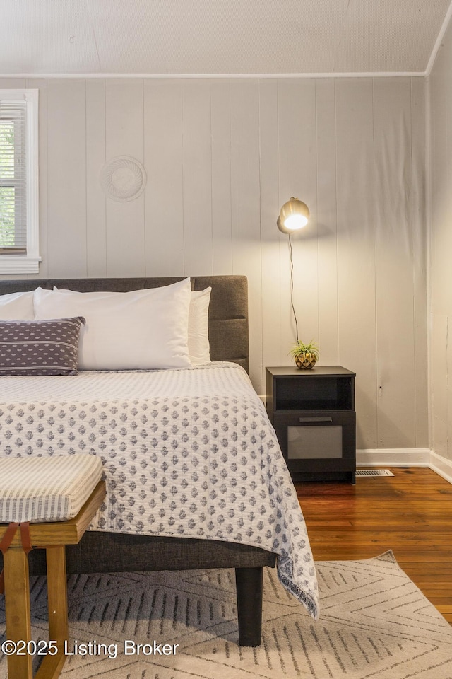 bedroom featuring dark wood-type flooring and wooden walls