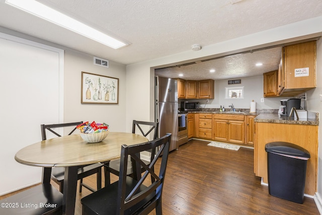 dining space featuring dark hardwood / wood-style floors, sink, and a textured ceiling