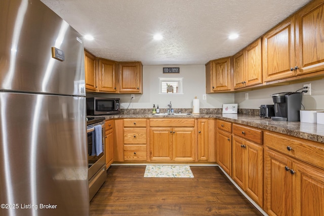 kitchen with dark hardwood / wood-style flooring, sink, a textured ceiling, and appliances with stainless steel finishes