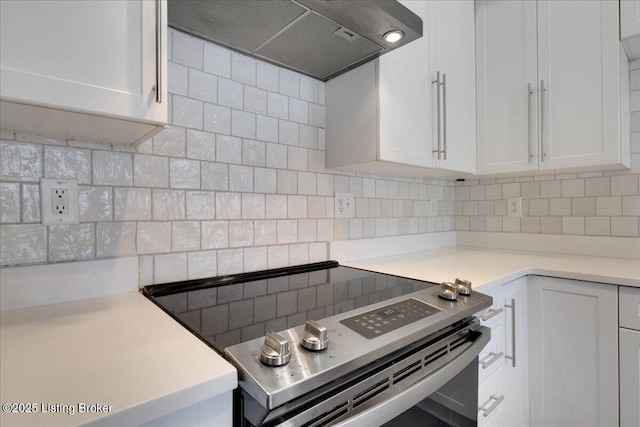 kitchen with ventilation hood, white cabinets, stainless steel range with electric cooktop, and tasteful backsplash