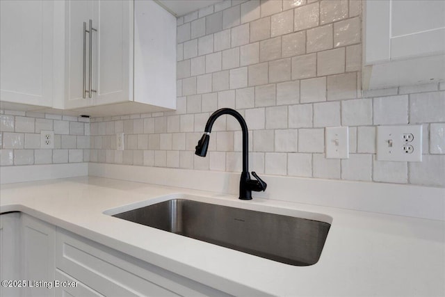 details featuring white cabinets, tasteful backsplash, and sink