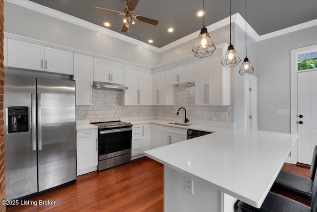 kitchen with appliances with stainless steel finishes, a breakfast bar, sink, decorative light fixtures, and white cabinets