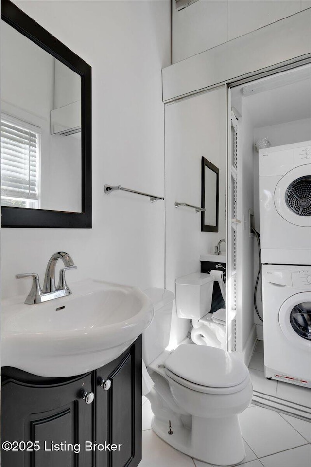 bathroom featuring tile patterned floors, vanity, stacked washer and clothes dryer, and toilet