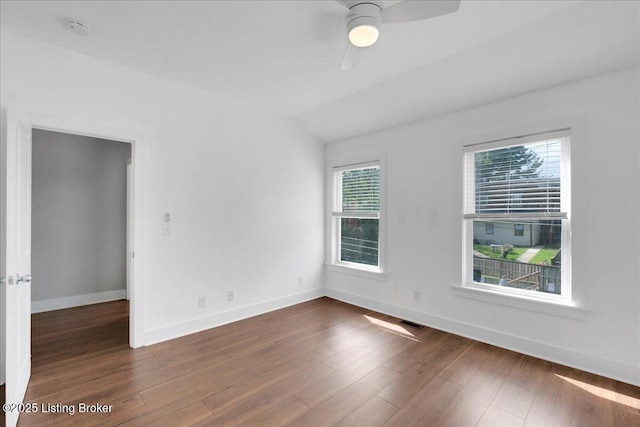 empty room with ceiling fan, dark hardwood / wood-style flooring, and vaulted ceiling