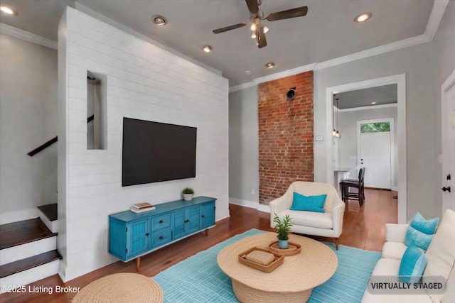 living room featuring dark hardwood / wood-style floors, ceiling fan, ornamental molding, and brick wall