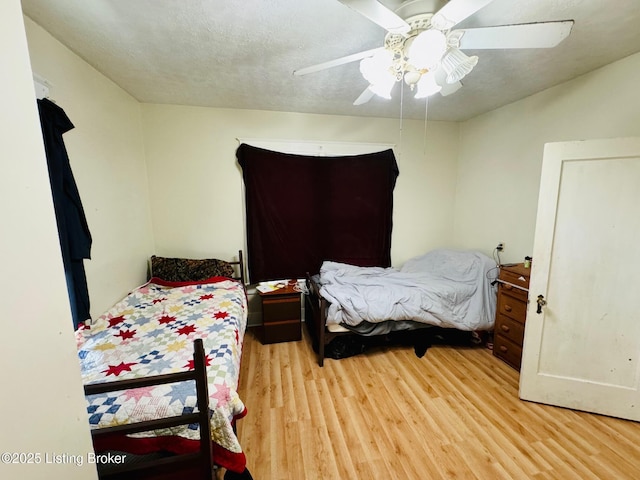 bedroom with a textured ceiling, light hardwood / wood-style flooring, and ceiling fan