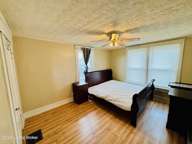 bedroom featuring ceiling fan, hardwood / wood-style floors, and a textured ceiling