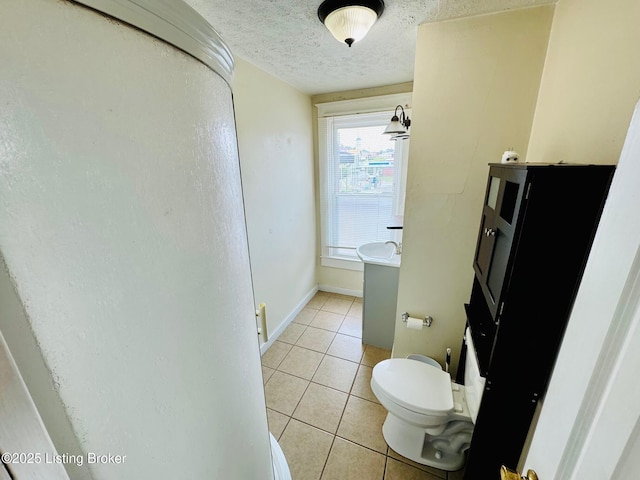 bathroom with tile patterned flooring, toilet, and a textured ceiling