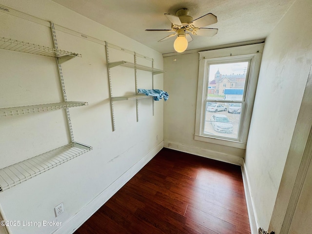 spacious closet with ceiling fan and dark wood-type flooring