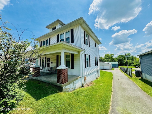 view of front of home with an outbuilding, a porch, a garage, and a front lawn