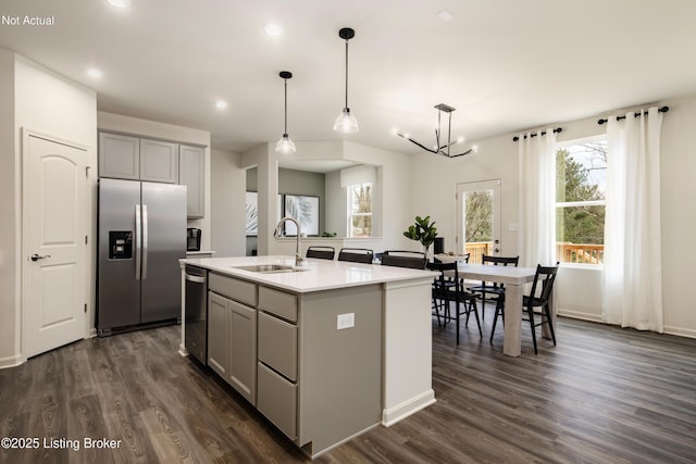 kitchen featuring gray cabinetry, stainless steel appliances, sink, decorative light fixtures, and an island with sink