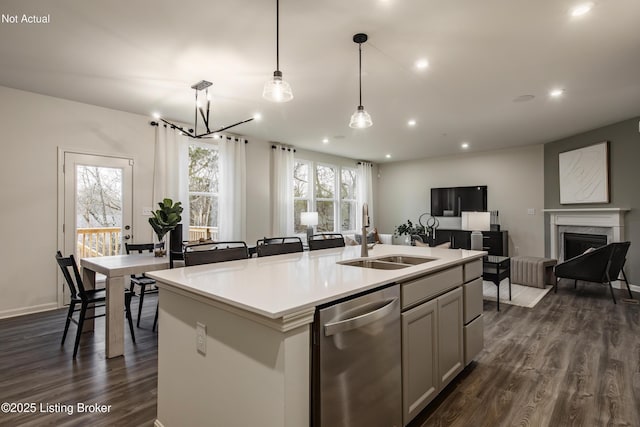 kitchen with pendant lighting, dishwasher, a center island with sink, sink, and dark hardwood / wood-style floors