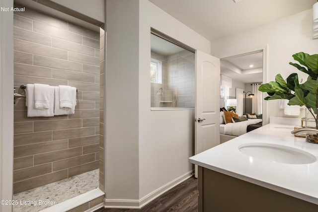 bathroom with tiled shower, vanity, and hardwood / wood-style flooring