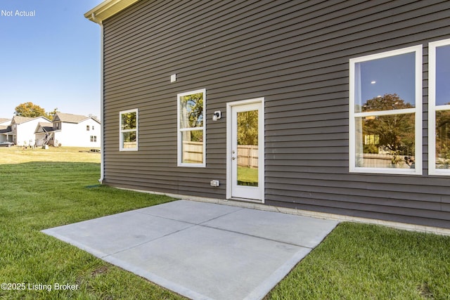 view of exterior entry featuring a yard and a patio area