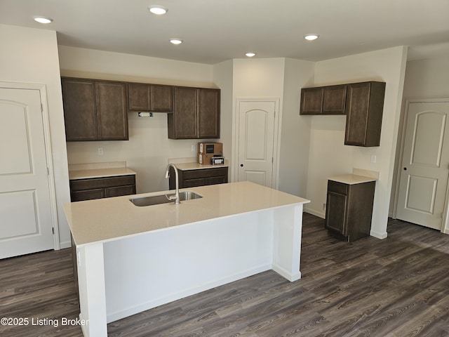 kitchen with dark brown cabinetry, recessed lighting, a sink, dark wood-style floors, and a center island with sink