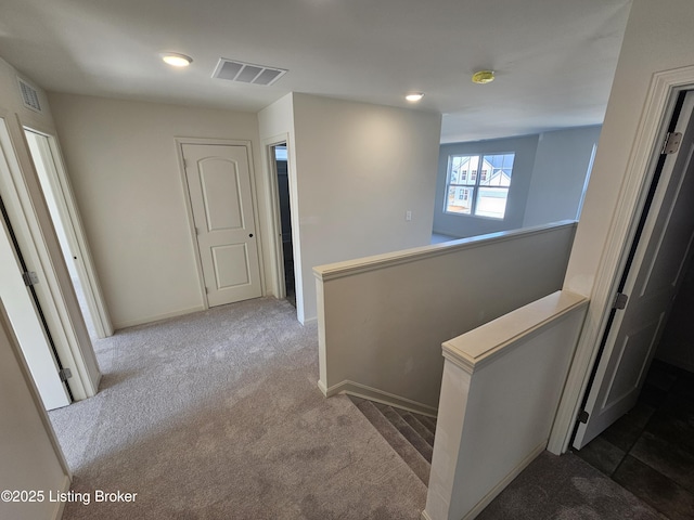 corridor with visible vents, carpet floors, an upstairs landing, and baseboards