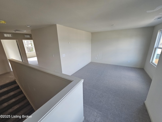 unfurnished room featuring carpet, visible vents, and baseboards