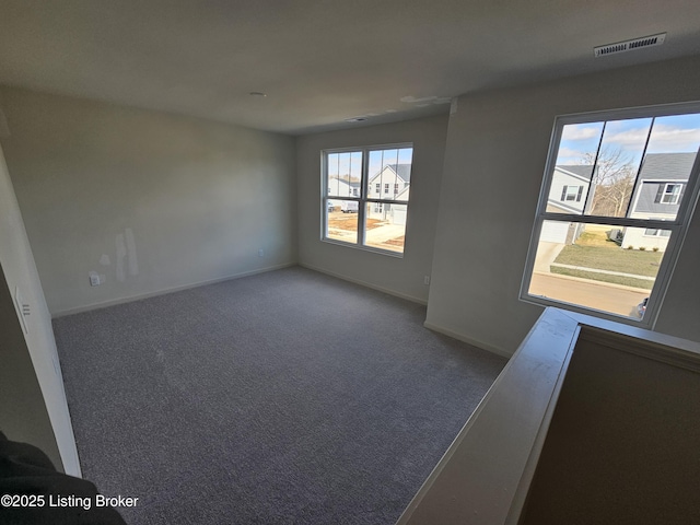 spare room featuring carpet floors, visible vents, and baseboards