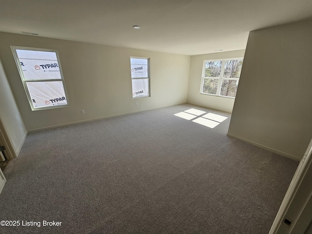 empty room featuring carpet floors, visible vents, and baseboards