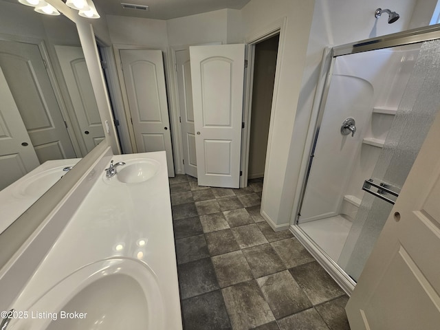 full bathroom with stone finish flooring, a sink, visible vents, double vanity, and a stall shower