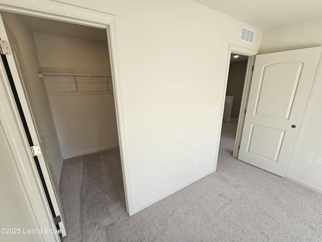 unfurnished bedroom with a spacious closet, a closet, carpet flooring, and visible vents