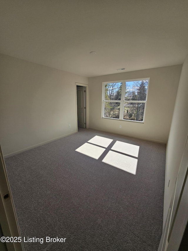 carpeted empty room featuring baseboards and visible vents