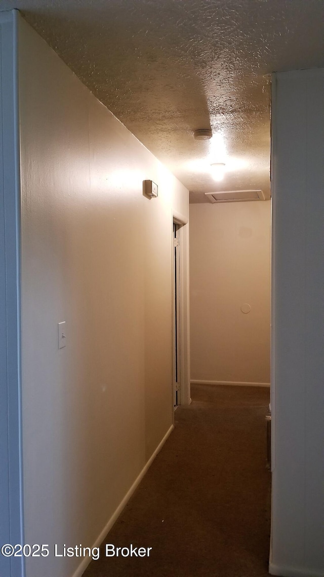 hallway with a textured ceiling and carpet