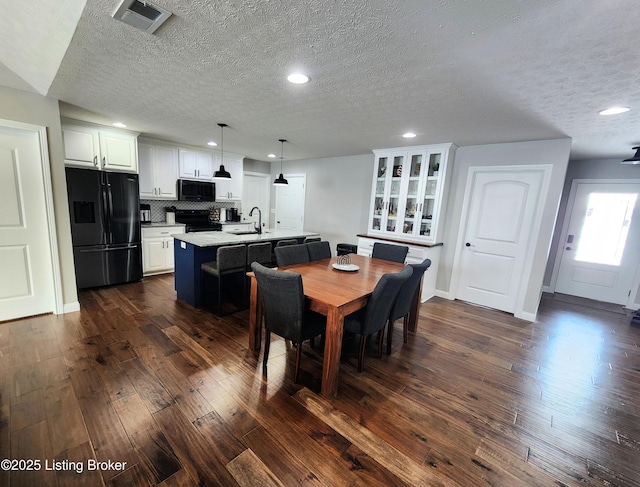 dining space with a textured ceiling, dark hardwood / wood-style flooring, and sink