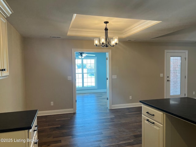 kitchen featuring a raised ceiling, dark wood-type flooring, white cabinets, and pendant lighting