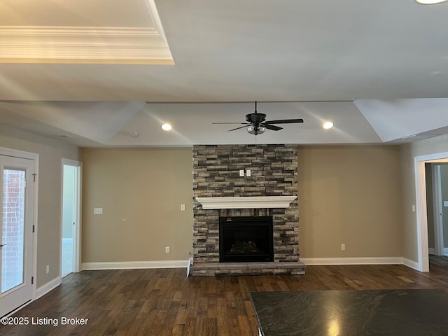 unfurnished living room featuring dark wood-type flooring, a raised ceiling, crown molding, ceiling fan, and a fireplace