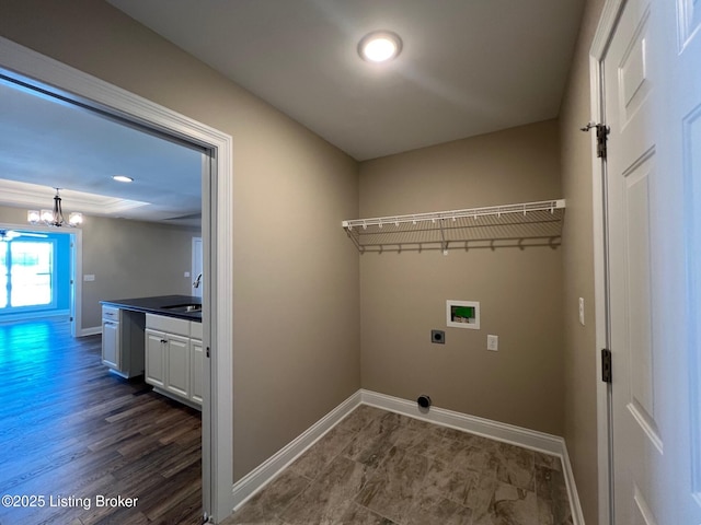 clothes washing area with hookup for an electric dryer, hookup for a washing machine, an inviting chandelier, and sink