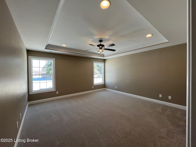 carpeted empty room with a raised ceiling, ceiling fan, and crown molding