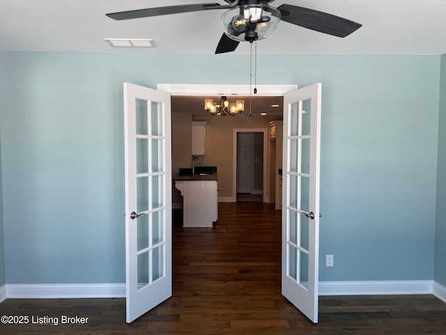 empty room featuring ceiling fan with notable chandelier, french doors, and dark hardwood / wood-style flooring