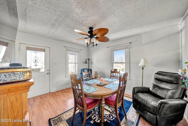 dining room with ceiling fan, light wood-type flooring, a textured ceiling, and a wealth of natural light