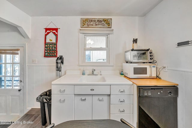 kitchen featuring dishwasher, dark hardwood / wood-style flooring, white cabinetry, and sink