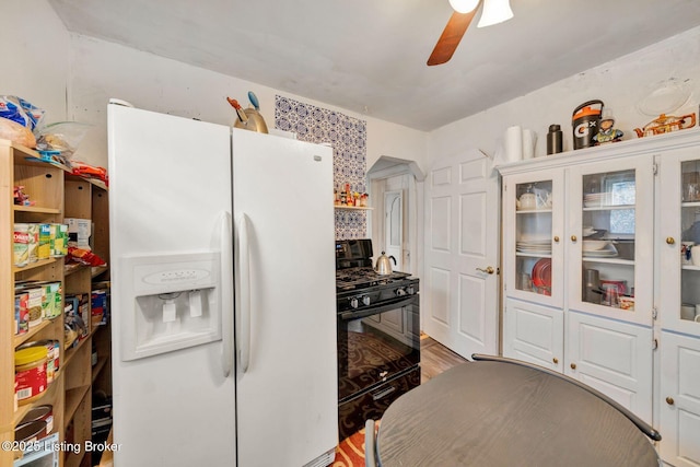 kitchen featuring ceiling fan, black gas stove, white cabinets, and white refrigerator with ice dispenser