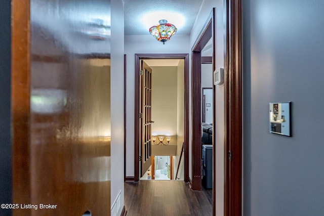 corridor featuring a textured ceiling and dark wood-type flooring