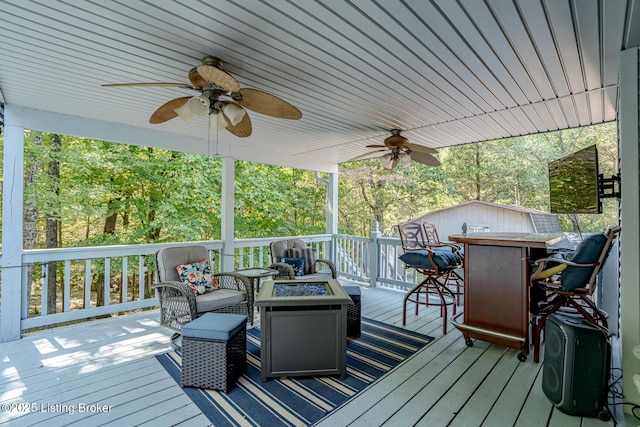 deck with ceiling fan, a bar, and an outdoor fire pit