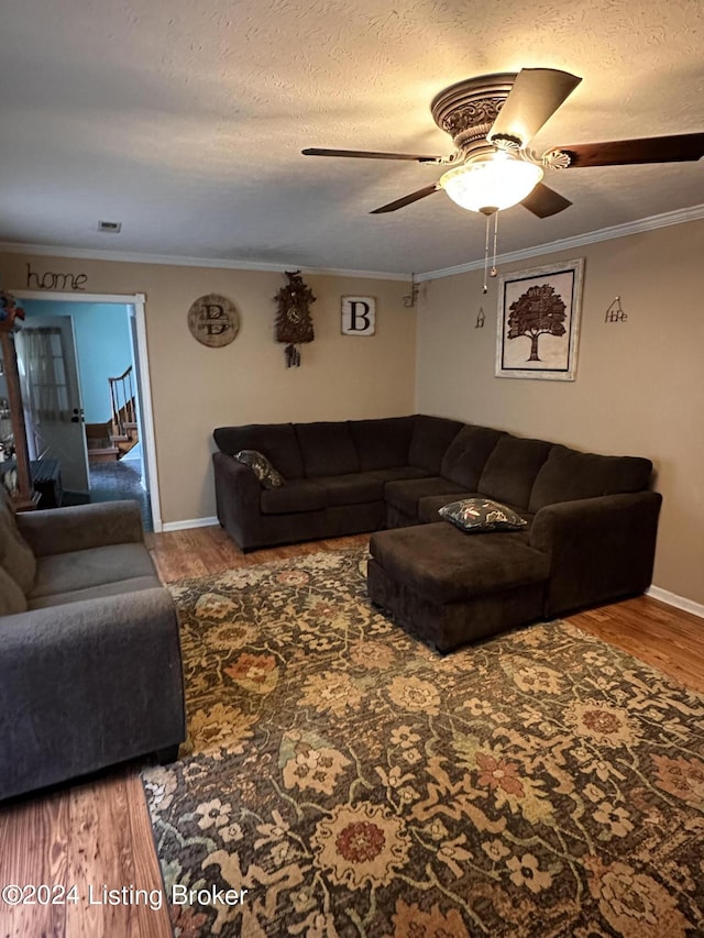 living room with hardwood / wood-style floors, ceiling fan, ornamental molding, and a textured ceiling