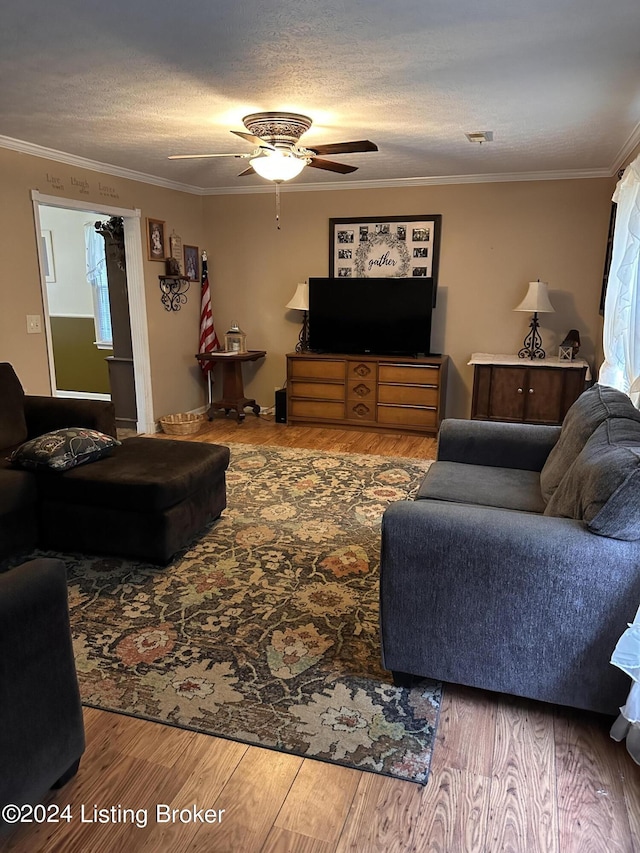 living room featuring a textured ceiling, ceiling fan, wood-type flooring, and crown molding