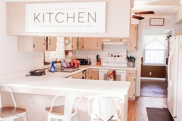 kitchen with a kitchen breakfast bar, kitchen peninsula, sink, and white appliances