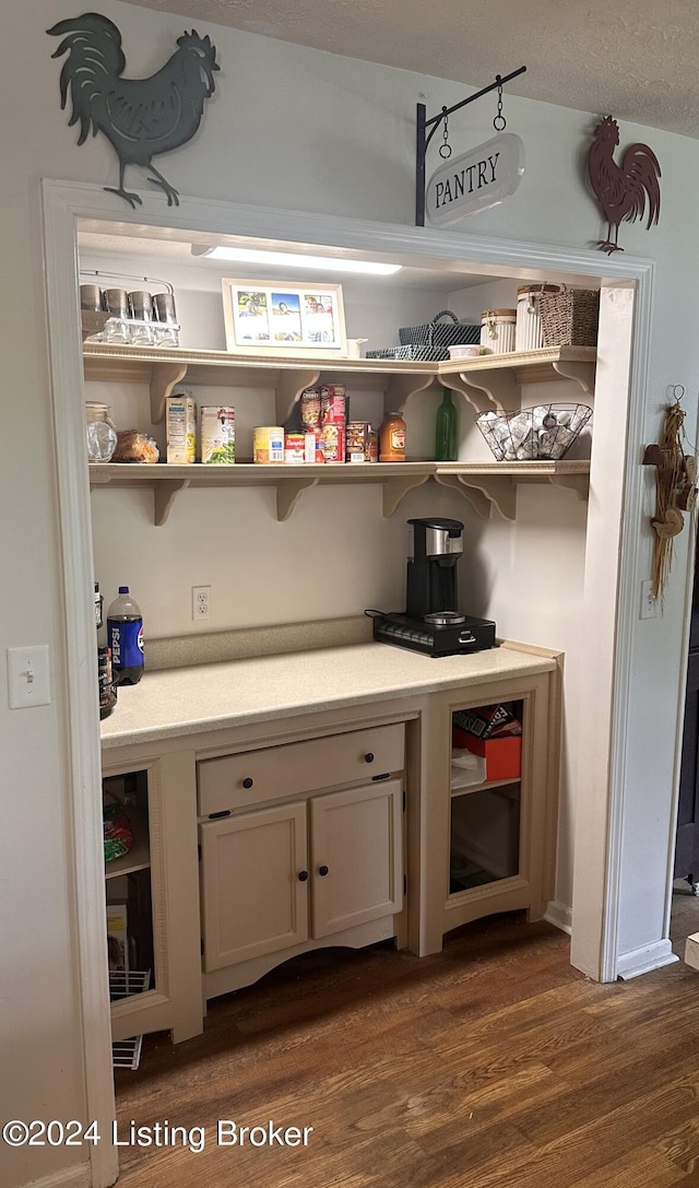 bar with dark hardwood / wood-style flooring and white cabinets