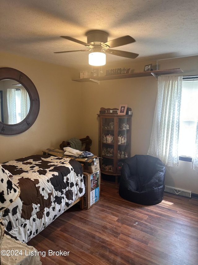 bedroom featuring ceiling fan, a textured ceiling, and dark wood-type flooring