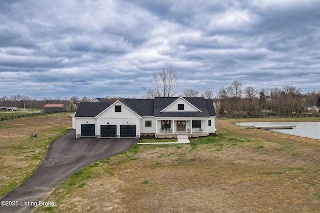 modern inspired farmhouse featuring a garage, a front yard, and covered porch